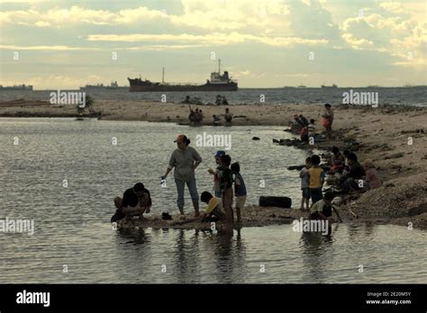 People having a recreational time on Cilincing beach in the coastal area of Jakarta, with a ship ...