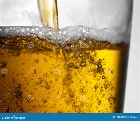 Closeup Of Beer Pouring Into Clear Glass With Bubbles And Froth Stock