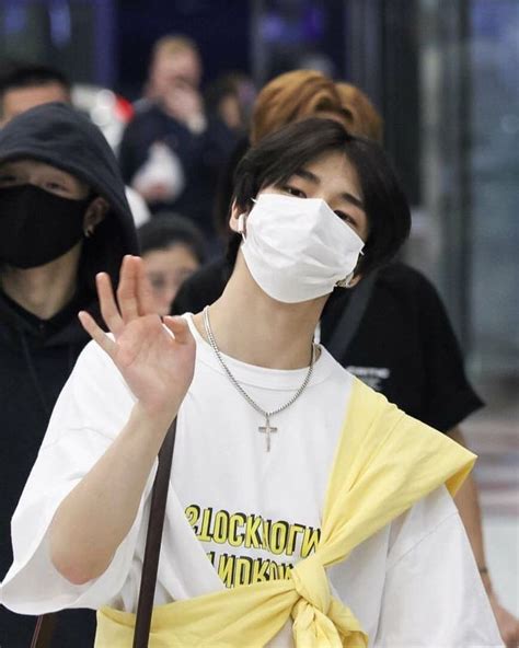 A Man Wearing A Face Mask While Walking Through An Airport With Other