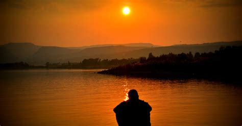 Silhouette of Person Sitting Beside Body of Water · Free Stock Photo