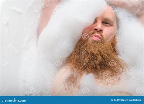 Portrait Of A Bald Man With A Long Red Beard Takes A Bath With Foam Top View On A Cheerful