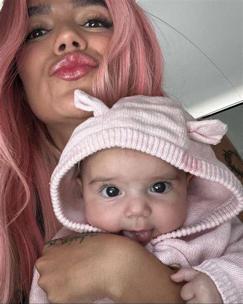 A Woman With Pink Hair Holding A Baby