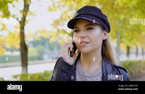 Perky Blonde Woman Is Wearing Black Leather Cap Is Walking Over Autumn Alley In Stock Video