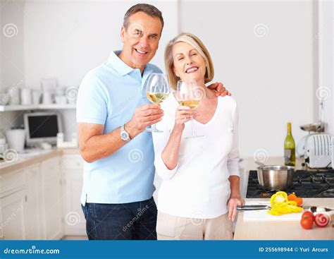 Cheerful Senior Couple Toasting Wine Glasses At Kitchen Portrait Of A