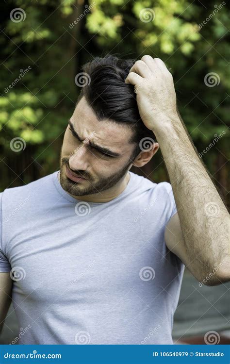 Confused Young Man Scratching His Head Looking Down Stock Image