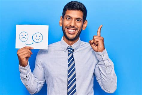 Young Latin Man Holding Sad To Happy Emotion Paper Surprised with an ...