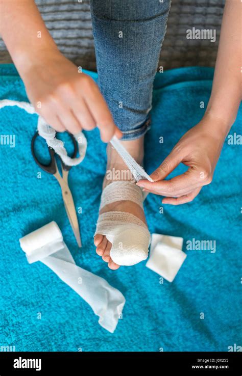 Woman Bandaging Her Injured Leg On Sofa At Home Stock Photo Alamy