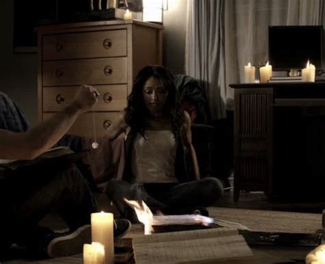 Two People Sitting On The Floor In A Living Room With Candles And Books