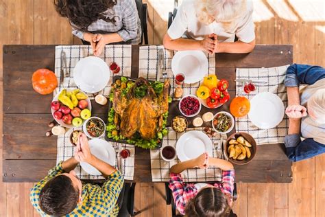 Familia Sentada A La Mesa Y Rezando Foto Gratis