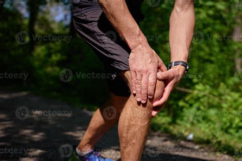 Man suffering from knee pain during running in green park 63543250