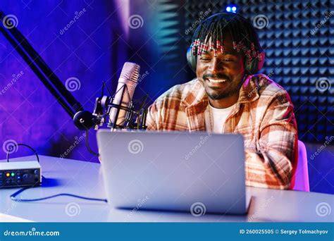 African Radio Host Sitting At Desk Recording In Studio With Microphone