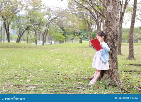 Pretty Little Child Girl Reading Book In Park Outdoor Standing Lean