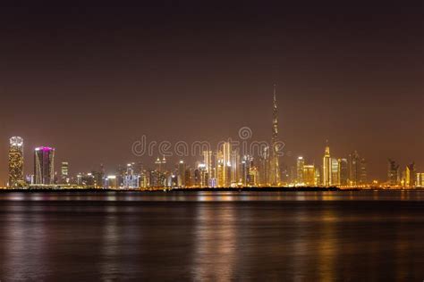 Dubai Business Bay Skyline at Night with Colorful Illuminated Buildings and Calm Dubai Creek ...