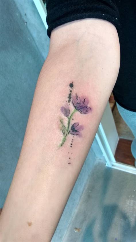 Watercolor style purple flower on the forearm.