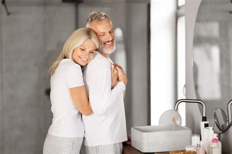 Un couple mature heureux s embrassant dans l intérieur de la salle de bain Photo Premium