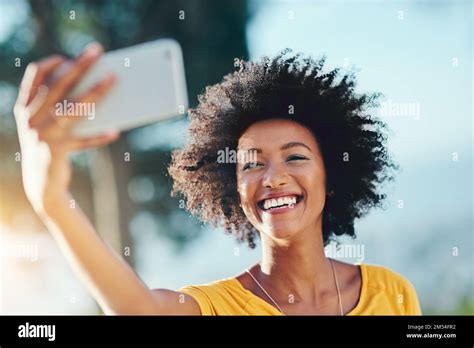 Sunshine And Selfies An Attractive Young Woman Taking Selfies While Standing Outside Stock