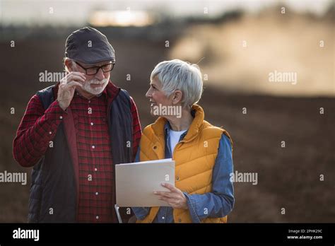 Mature Farmers Man And Woman Standing In Field And Writing Notes While