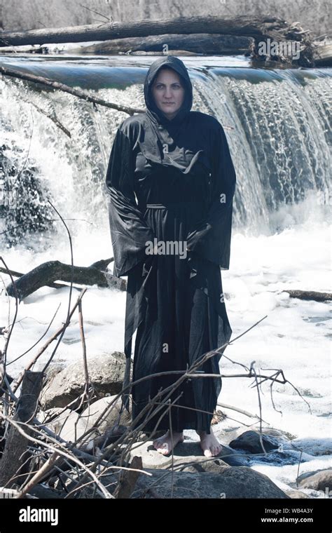 Hooded Woman In Black Robes In Front Of The Waterfall Witches