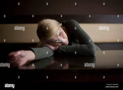 Blonde Woman Looking Sad Leaning Her Body Over A Table In A Bar Stock