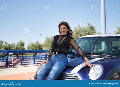 Attractive Mature Woman In Black Transparent Shirt And Jeans Smiling