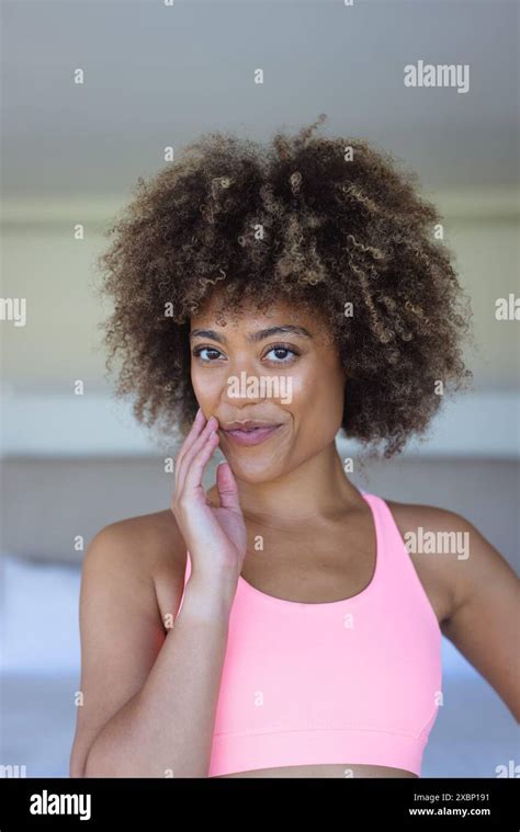 Happy Biracial Woman With Curly Hair Wearing Pink Sports Bra Smiling