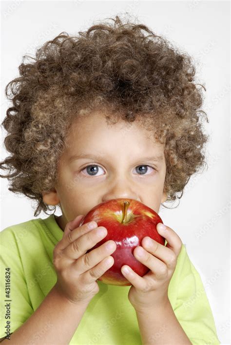 Niño comiendo una manzana roja sujetando una manzana fruta foto de