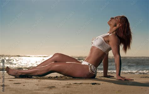 Sensuous Female Model Sitting In Bikini At Beach Against Sky Stock Photo Adobe Stock