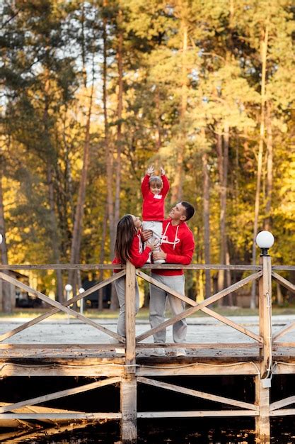 Familia en un paseo por el parque de otoño cerca del estanque padre y