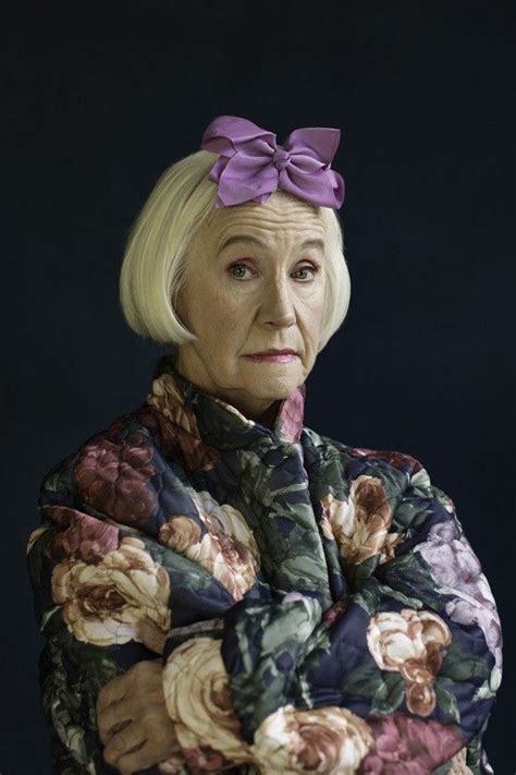 An Older Woman With Her Arms Crossed Wearing A Flowery Jacket And