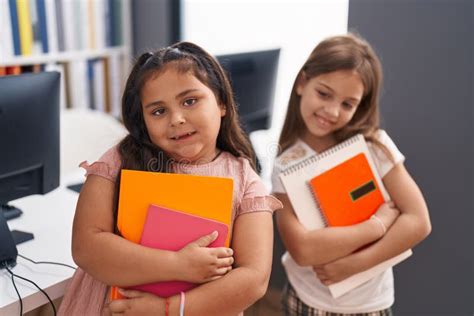 kids students smiling confident holding books  classroom stock