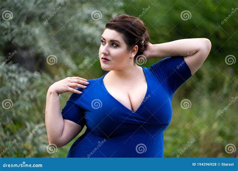 Plus Size Fashion Model In Blue Dress With A Deep Neckline Outdoors