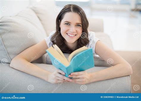 Peaceful Cute Woman Lying On A Cosy Couch Reading Book Stock Image