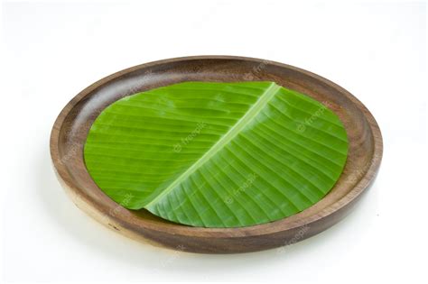 Premium Photo | Banana leaf fresh green banana leaf cut in circular shape and placed on a wooden ...