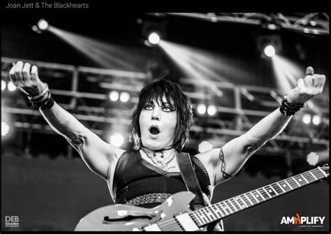 An Image Of A Woman With Her Hands In The Air And Holding A Guitar On Stage