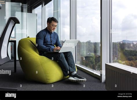 Asian Young Office Worker Sitting On Soft Ottoman Chair Programmer