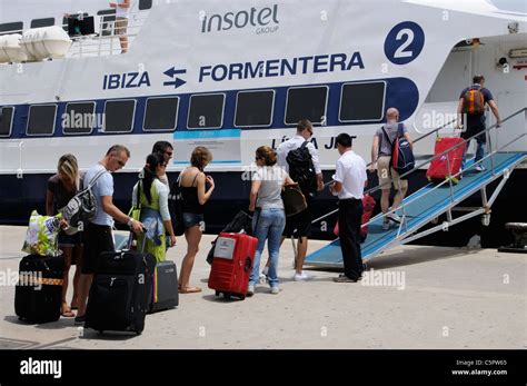 Holiday Makers With Luggage On Wheels Boarding A Ferry At Eivissa Ibiza