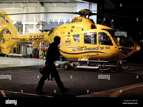 A Pilot Walks Past A Scottish Ambulance Service Helicopter In Its