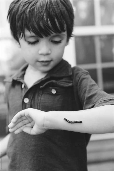 "Boy Stares At A Caterpillar Crawling On His Arm" by Stocksy