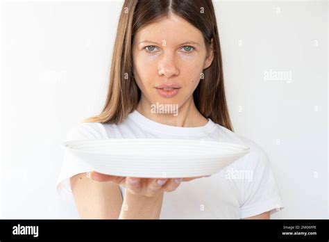 The Girl Is Holding An Empty White Plate On A White Background The