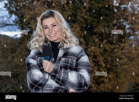 Blonde Reporter In Coat And Microphone Smiling At The Camera Stock Photo Alamy