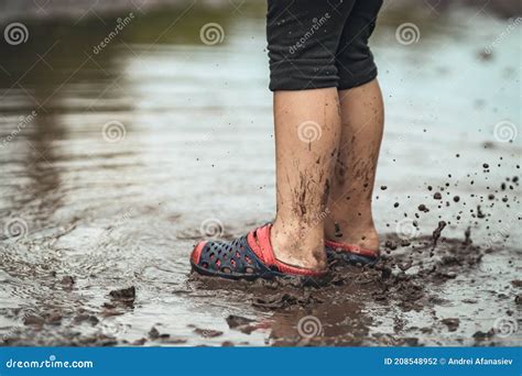 Children`s Feet Walking In A Muddy Puddle After The Rain Stock Photo