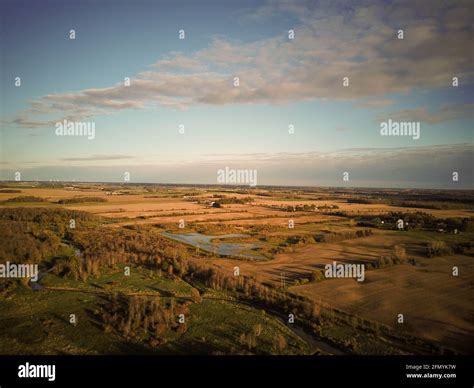 Aerial View Of Small River Flowing Through Green Marshy Riparian