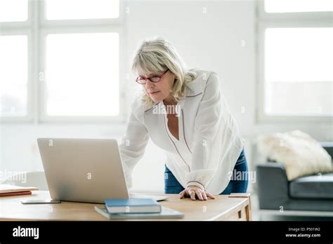 Mature Businesswoman Working On Laptop At Desk Stock Photo Alamy