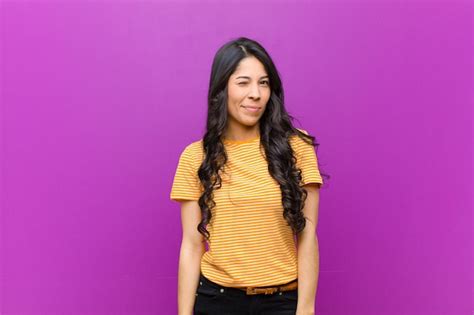 Joven mujer latina que parece feliz y amigable sonriendo y guiñándole un ojo con una actitud