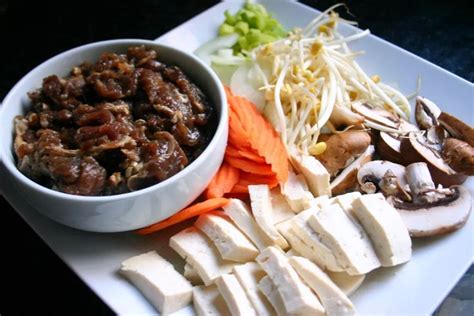 A White Plate Topped With Tofu Carrots And Mushrooms