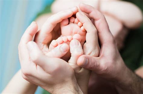 Os Pés Do Bebê Recém nascido Nas Mãos Da Mamã E Do Paizinho Formando