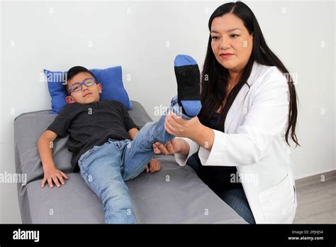 Latina Kinderärztin Ärztin besucht einen 7 jährigen Jungen in ihrer Praxis untersucht sein Bein