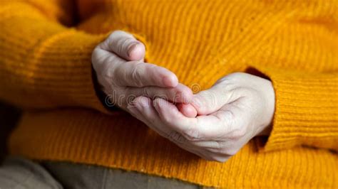 Mature Woman Touches Fingers On Hand With Unsure Actions Stock Photo