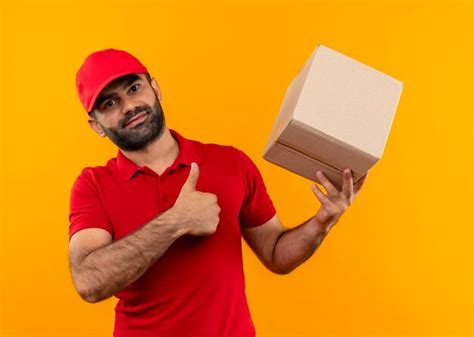 Free Photo Bearded Delivery Man In Red Uniform And Cap Holding Box