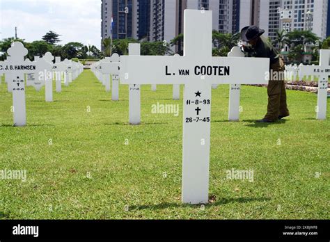 Los trabajadores limpian la lápida del soldado del cementerio holandés